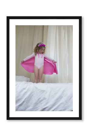 Young girl dressed up as a princess standing on bed