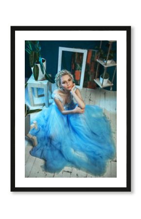 Beautiful model wearing light blue dress is posing in a studio 
