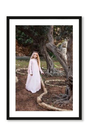 a little princess of spirits and fairies stands in the enchanted mysterious magic forest in a wedding dress with a veil and crown