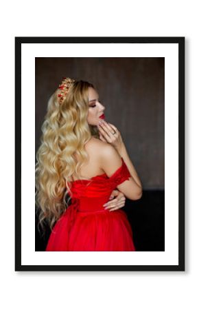 Beautiful princess blonde in red dress and with diadem, stands with back