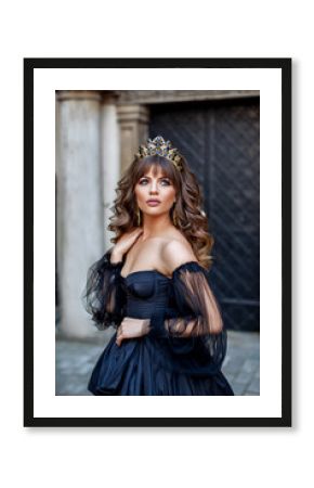 Portrait of princess in lush black dress and diadem in ancient city of Lviv