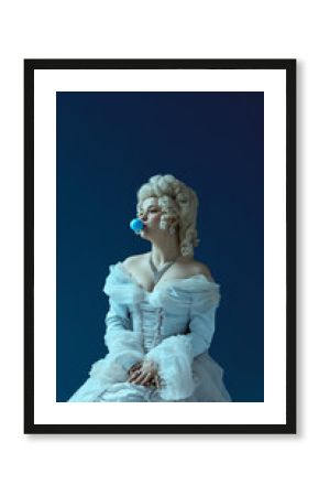 Cheeky mood. Young beautiful woman, aristocrat girl with powdered wig blowing blue bubble gum. Medieval elegance clashing with modern trends, art and irony, playful portrait concept.