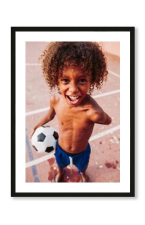 Portrait of a boy holding a soccer ball standing on a soccer field