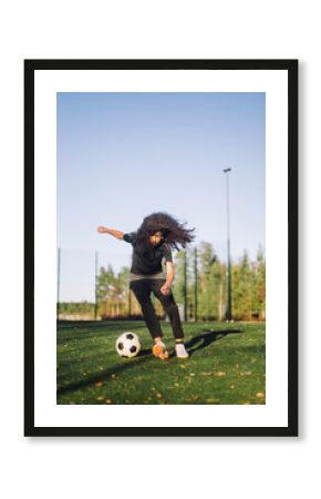 Girl playing soccer on sports field during sunny day