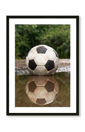 Dirty soccer ball in muddy puddle outdoors