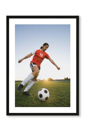 Mixed race woman kicking soccer ball