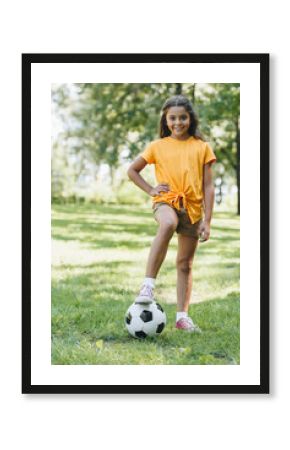 cute happy child standing with soccer ball and smiling at camera in park