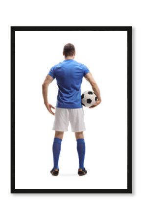 Full length rear shot of a soccer player with a ball under arm