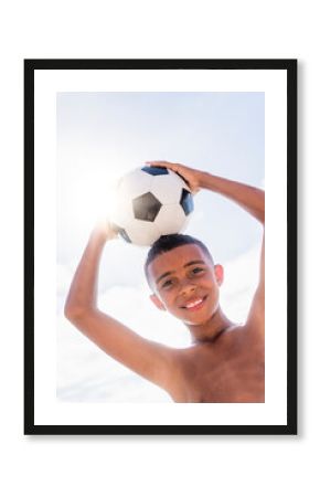 Boy (10-11) holding soccer ball on head