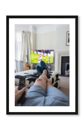 POV man watching soccer match on TV in living room