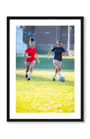 Teenage girl soccer players running after ball