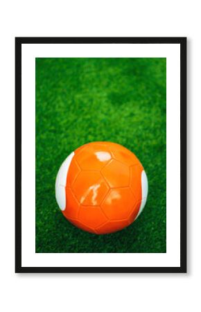 Orange soccer ball on artificial grass pitch