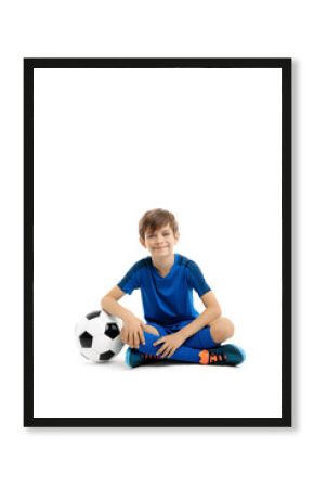 Smiling young boy posing with classic soccer ball on the floor over white background
