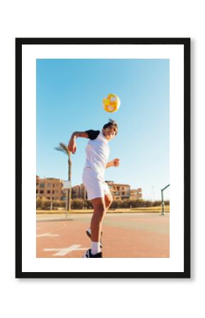 Boy heading soccer ball on sports court against sky