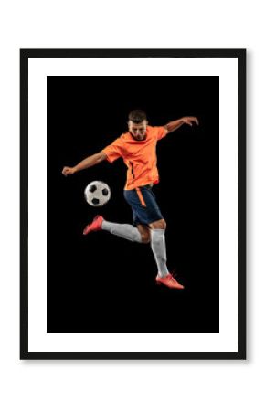 Studio shot of professional male football soccer player in motion isolated on dark background. Concept of sport, goals, competition, hobby, achievements