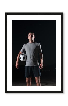 portrait of a young handsome soccer player man on a street playing with a football ball.