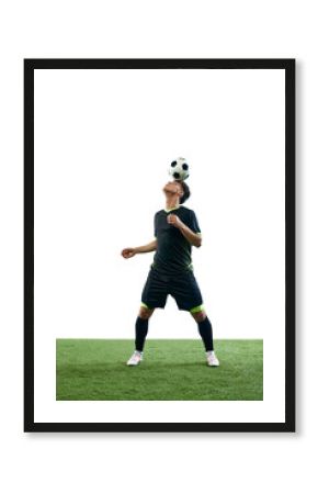 Full-length of young guy, soccer player during game, balancing ball on head isolated over white background with grass flooring. Concept of sport, game, competition, championship, active lifestyle