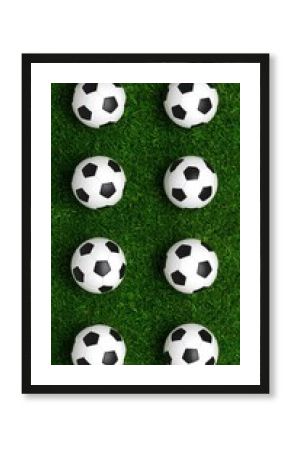 Eight soccer balls arranged vertically on green grass