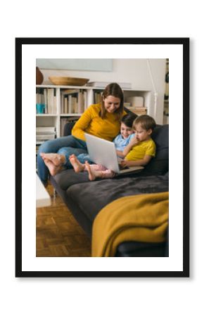 mother and her children using laptop computer while sitting on sofa at homemother and her children using laptop computer while sitting on sofa at home