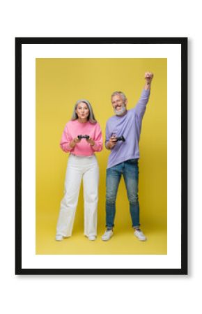 KYIV, UKRAINE - AUGUST 10, 2021: full length of happy interracial and mature couple winning video game on yellow