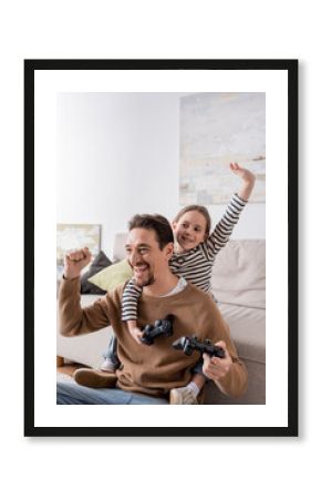 KYIV, UKRAINE - NOVEMBER 28, 2022: father and daughter holding joysticks and rejoicing after video game