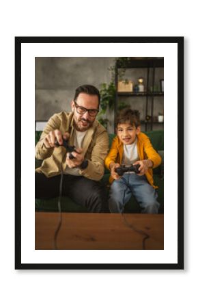 Father and son play video games with joystick and have fun at home