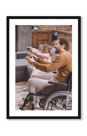 happy daughter and father on wheelchair playing video game with joysticks