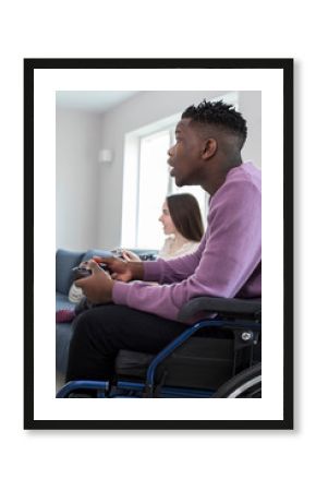 Teenage Boy In Wheelchair Playing Computer Video Game With Freind At Home