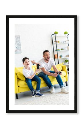 excited father and son playing Video Game on couch in Living Room