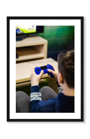 teenager playing a computer game, holding a joystick in his hands and looking at the screen