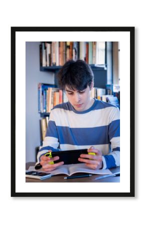 A teenager taking a break from homework to play on his game console