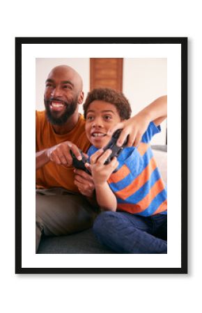 African American Father And Son Sitting On Sofa At Home Playing Video Game Together