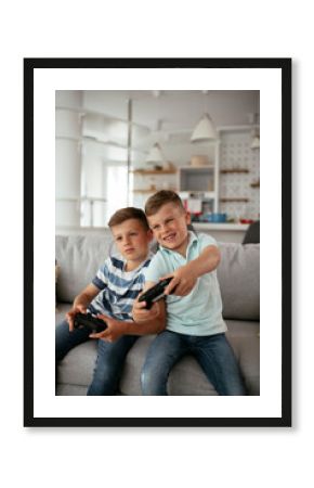 Happy brothers playing video games. Young brothers having fun while playing video games in living room