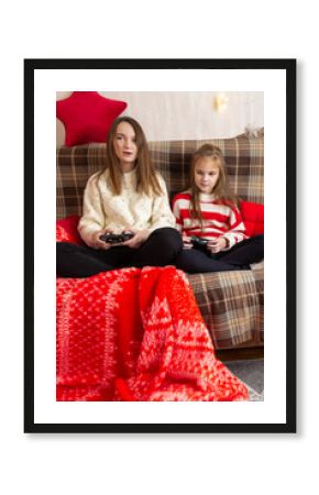 Happy family mother and daughter laugh and play video games together using a video game console on christmas holiday
