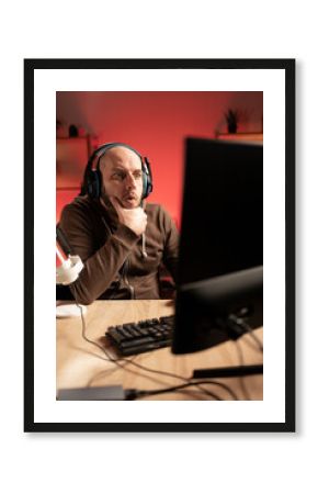 Gamer streamer playing online game on PC in dark room. Surprised looking at computer screen holding chin. e-Sport Games and Internet Championship.