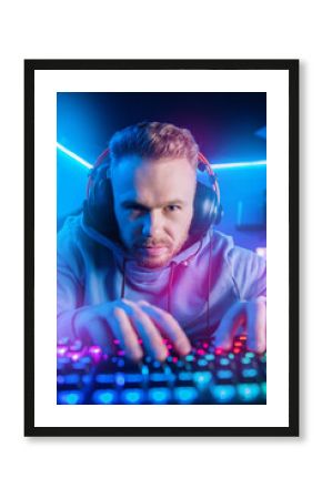 Streamer professional cyber sport gamer playing online computer game with headphones, Blurred Red and Blue background