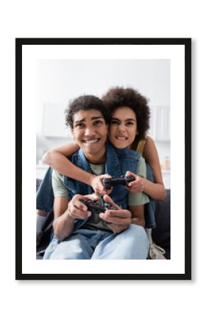 KYIV, UKRAINE - NOVEMBER 9, 2021: Focused african american couple playing video game on couch at home.