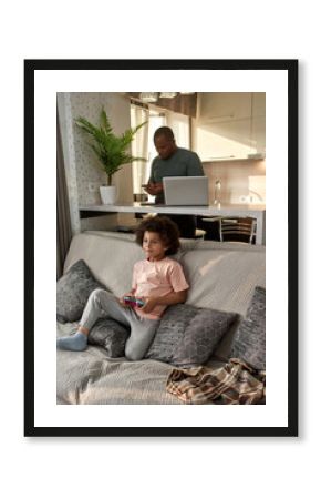 Boy playing video game and father using smartphone