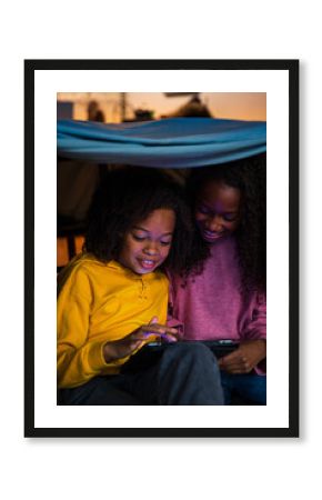 Sisters smiling while playing video game on digital tablet at home