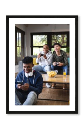 Vertical image of happy diverse male teenage friends playing video games at home