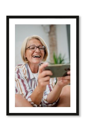 Mature woman use mobile smart phone play video games sit indoor