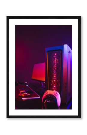 Vertical image of computer with video game accessories with copy space on neon background