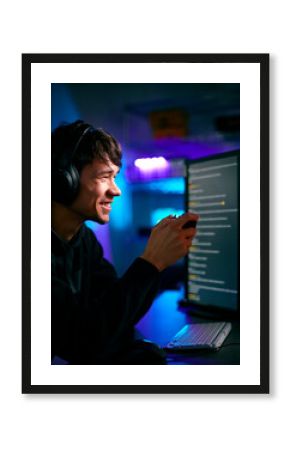 Low Key Lighting Shot Of Male Gamer In Front Of Computer Screens With Headphones And Controller