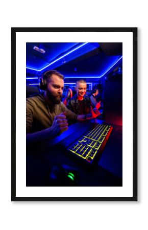 Gamer with headset is celebrating victory in video game in cybercafe.