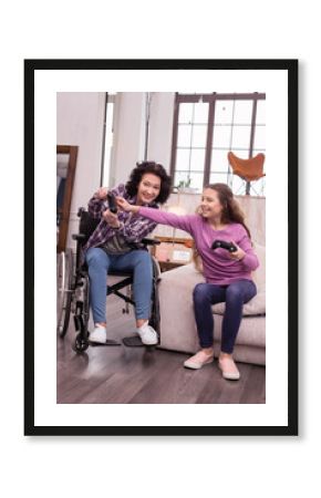 Push this. Happy incapacitated woman and girl using controller while sitting