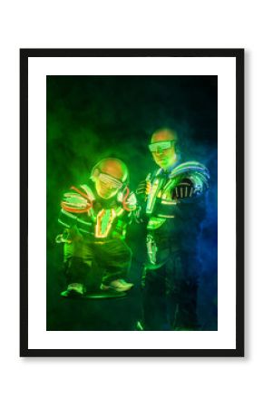 Mysterious man and midget in black wear, neon mask and gloves. Character pastors or wizards in robe from the future. Assassin with strong face expression. Fantasy book or computer game cover concept.