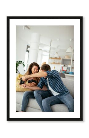 Husband and wife playing video game with joysticks in living room. Loving couple are playing video games at home.