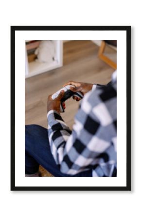 Cropped view of black man playing video game at blurred home