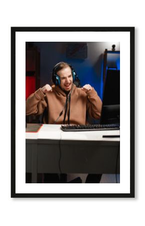 Happy successful gamer in headphones play video game online in neon light at night. Gaming at Home. Online Multiplayer Championship. Esport streaming game.
