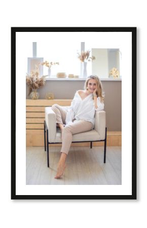 Portrait of a beautiful sensual young woman with blonde hair wearing a white shirt in home interior